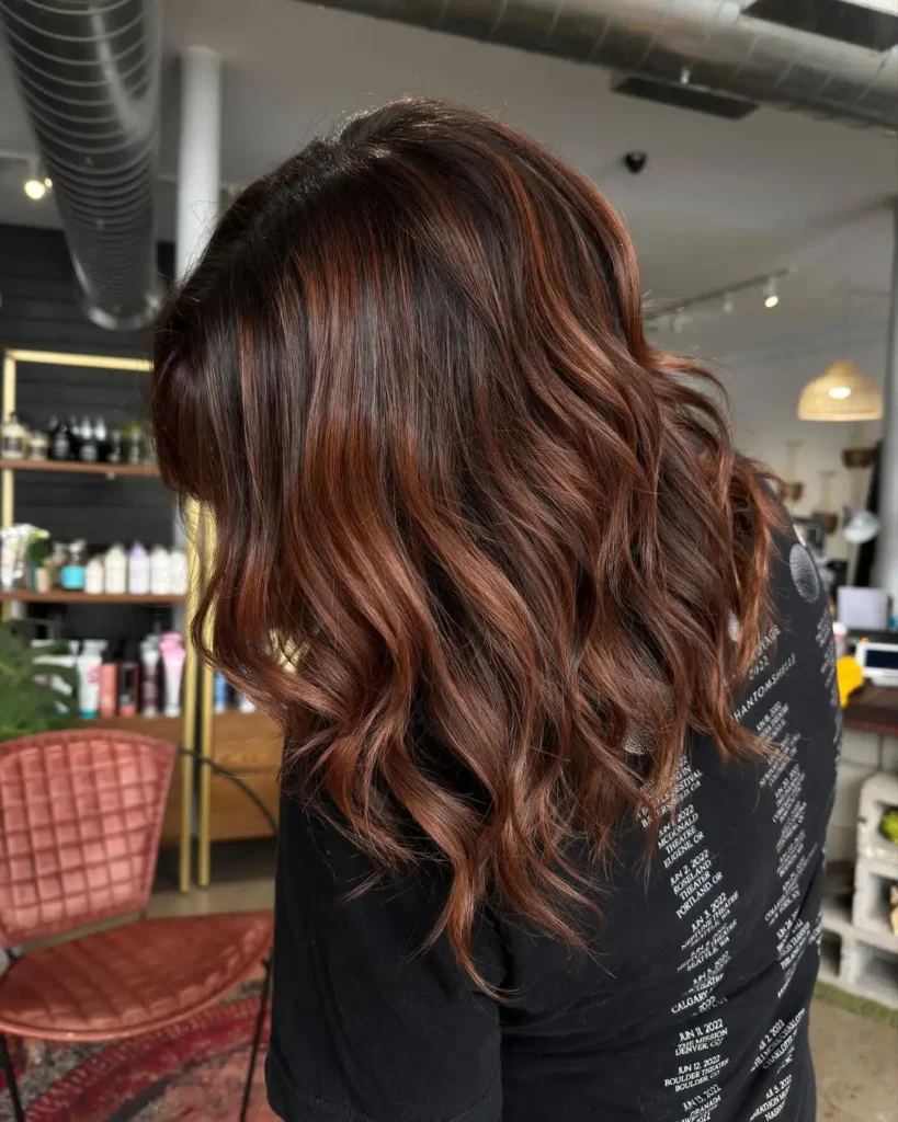 Rich brunette hair with warm copper undertones and soft dimensional waves