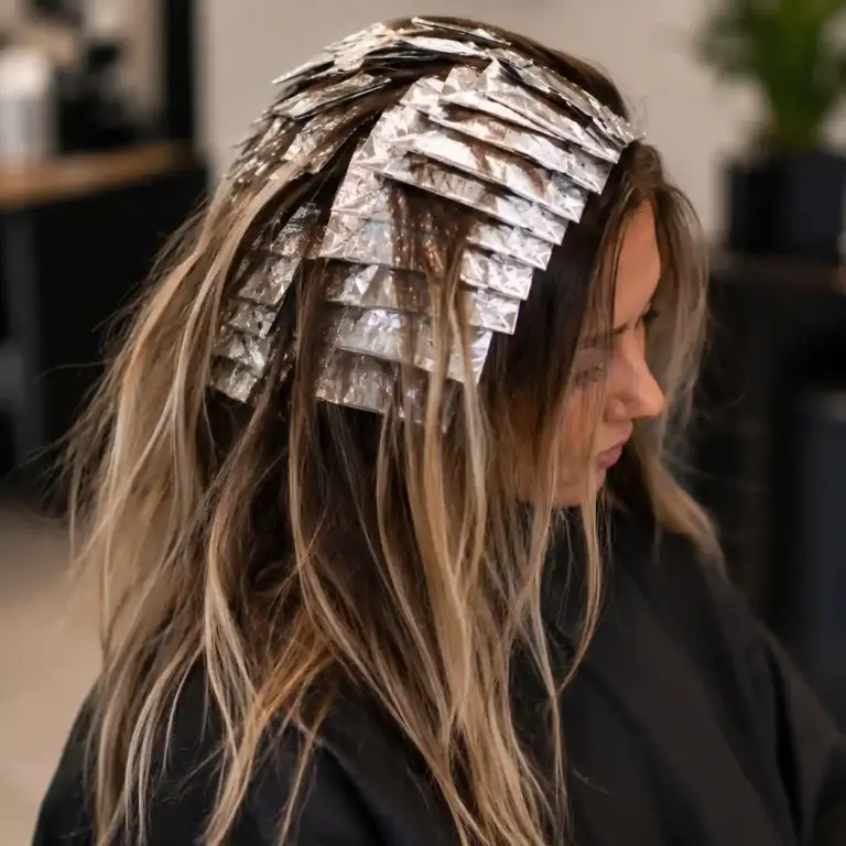 Client receiving a foilyage hair color service with foils placed throughout the hair to create brighter blonde highlights at Studio 303 in Englewood, CO.