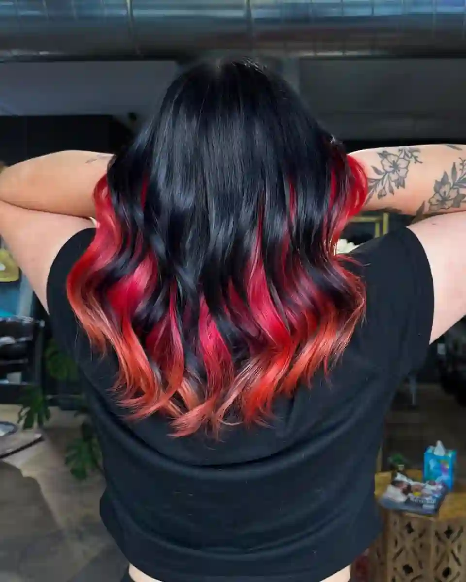 Black hair with red vivid balayage at Studio 303 in Englewood, CO.